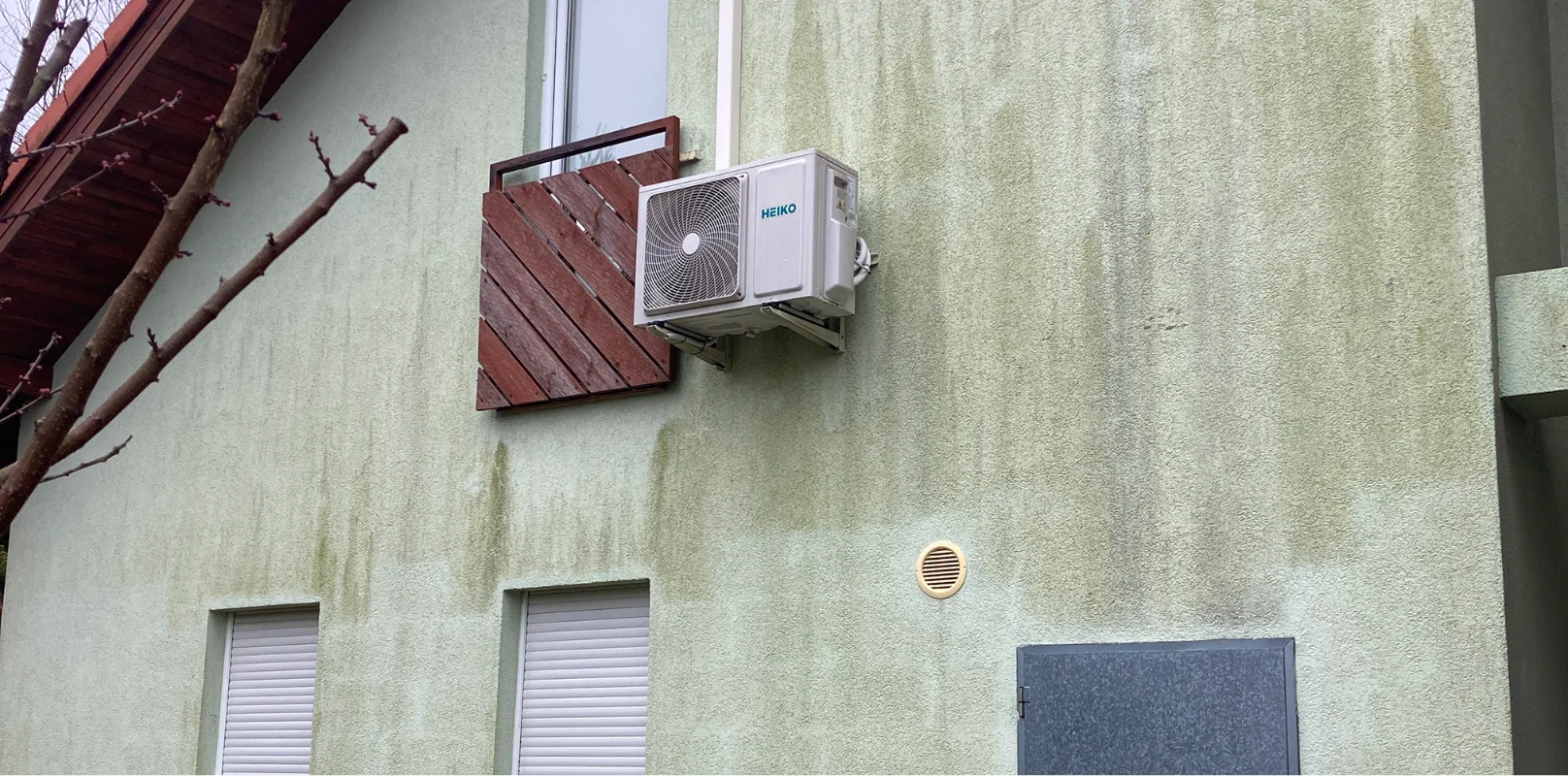 Zaniedbana zielona fasada budynku z zamkniętymi oknami i zewnętrzną jednostką klimatyzacji – Mycie elewacji